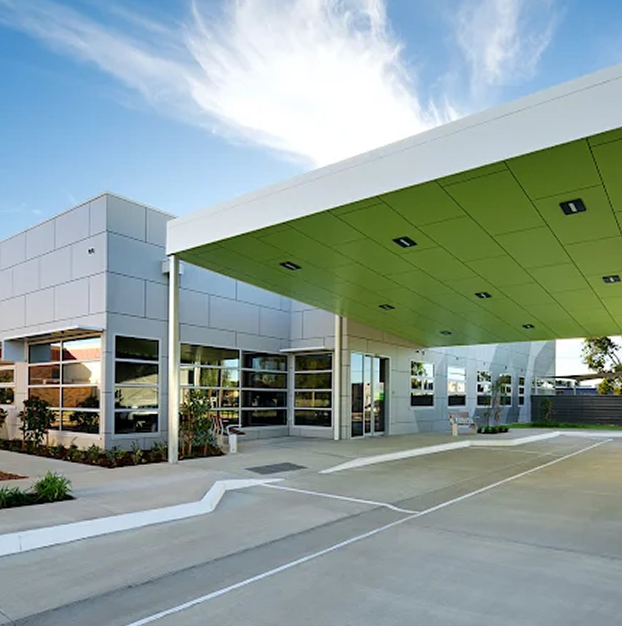 Modern building with large green canopy at entrance, extensive windows, and landscaped surroundings under a blue sky with wispy clouds, reflecting the contemporary design trends seen throughout the Loddon-Mallee Region.