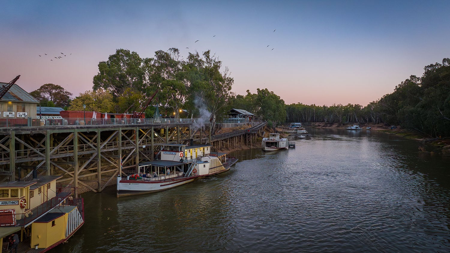 Wooden wharf with moored paddle steamers on a calm river in the Loddon-Mallee Region