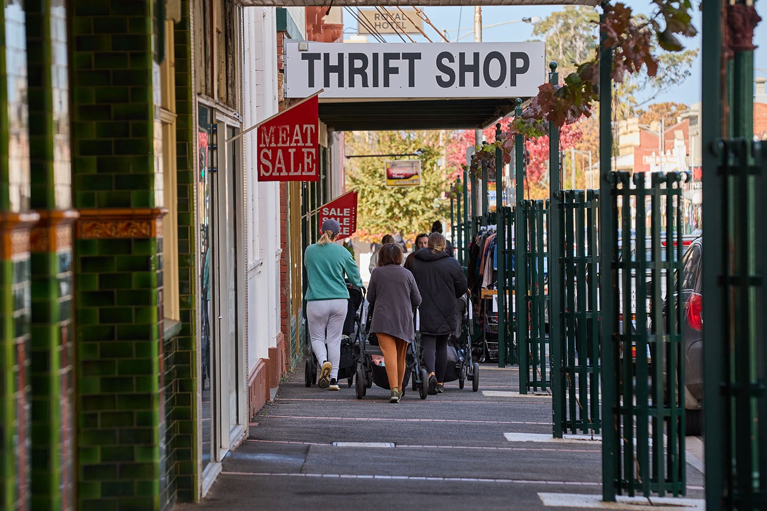 People walking down a small town street past a thrift store